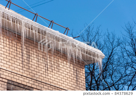 Roof Of The House With Snow And Icicles Overhanging 84378629