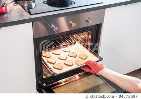 close-up partial view of person putting cookies into oven close-up partial view of person putting cookies into oven 84378697
