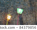 Bare trees in the public park. Bright yellow and green retro lanterns in the Moscow city public park. Concept of the beauty. Focus on foreground. Gray color of the background 84379856