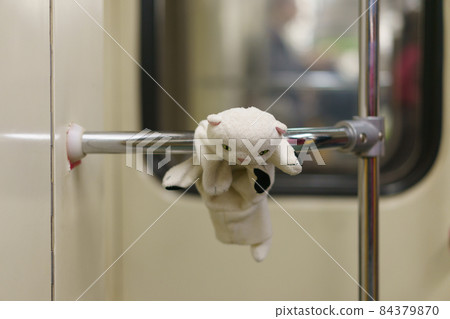 White toy kitten on the handrail in the subway. The child plays everywhere. Somebody lost it. It's suitable for greeting card design, postcard template. White toy kitten on the handrail in the subway. The child plays everywhere. Somebody lost it. It's suitable for greeting card design, postcard template. 84379870