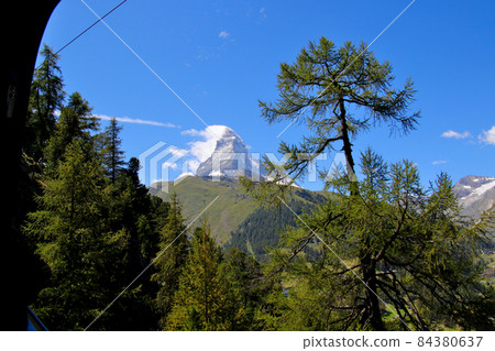 Matterhorn with impressive streaks in the sky, a little far away with the green foothills and trees Matterhorn with impressive streaks in the sky, a little far away with the green foothills and trees 84380637