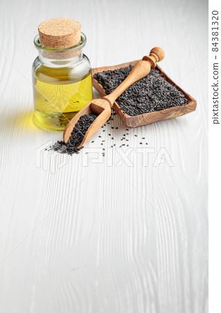 Sesame seeds and oil on an white wooden table. Sesame seeds and oil on an white wooden table. 84381320