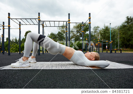 Resistance band fitness outdoors. Young athletic woman with perfect body in sportswear doing exercises with strap elastic in the city park Resistance band fitness outdoors. Young athletic woman with perfect body in sportswear doing exercises with strap elastic in the city park 84381721