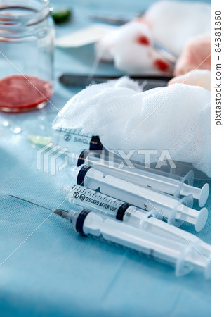 Many syringes on a blue sheet in operation room. Different sizes of syringes ready to be used Many syringes on a blue sheet in operation room. Different sizes of syringes ready to be used 84381860
