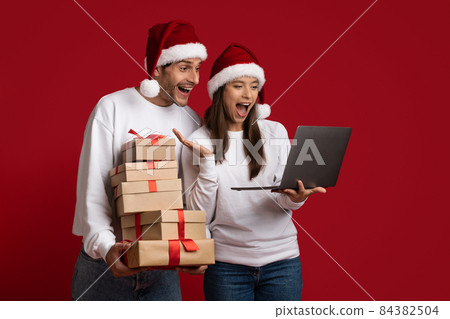 Online Sales. Excited Couple Holding Gift Boxes And Looking At Laptop Screen 84382504