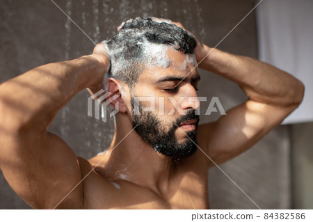 Handsome condifent young Arabic male model enjoying taking hot shower Handsome condifent young Arabic male model enjoying taking hot shower 84382586