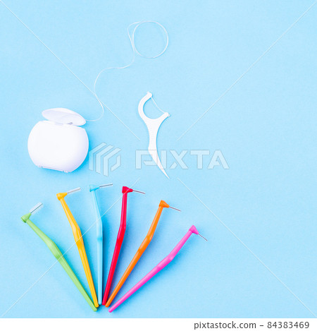 Tooth care and oral hygiene products, dental floss and interdental brush angles on blue, square format 84383469
