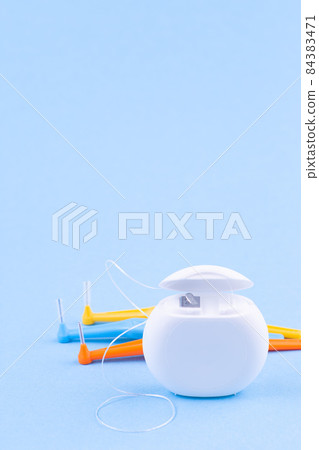 Dental floss and interdental brush angles on blue background, vertical, copy space 84383471