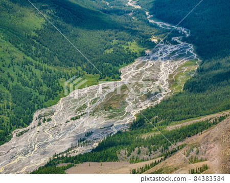 Glaciers melt, water flows into the valley. Picturesque highland green landscape with wide mountain river in valley. Awesome alpine view to motley mountain valley. Aerial view. 84383584