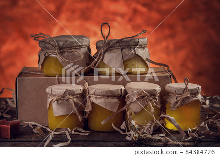 Six jars of honey on a wooden desk Six jars of honey on a wooden desk 84384726