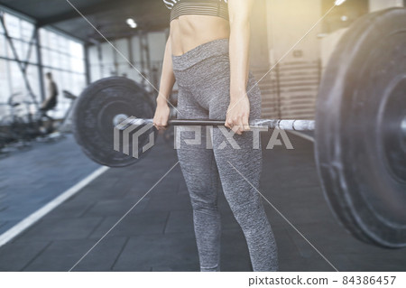 Young woman exercises in gym healthy lifestyle holding barbell close-up Young woman exercises in gym healthy lifestyle holding barbell close-up 84386457