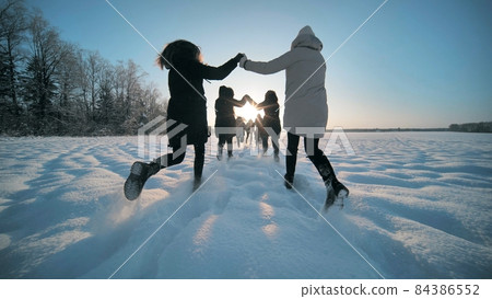 Cheerful girls run across the snow-covered field. Cheerful girls run across the snow-covered field. 84386552
