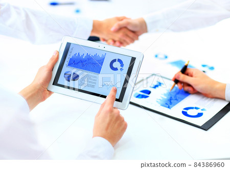 Image of human hand pointing at touchscreen with business document 84386960