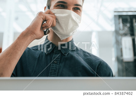 close up. a young man in a protective mask using a laptop 84387402