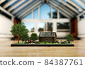 3D illustration in the room on the table is a phone and on it is a model of an old house in a rustic style with trees 84387761