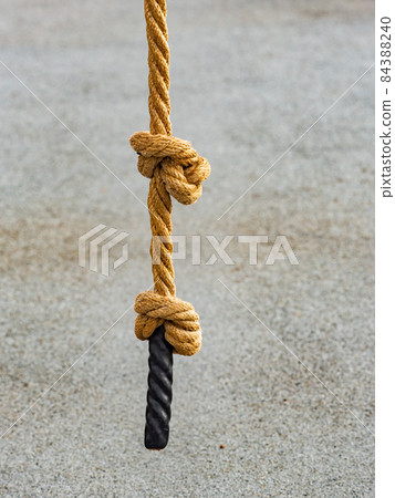 Knotted sports rope hanging from crossbar of horizontal bar Knotted sports rope hanging from crossbar of horizontal bar 84388240