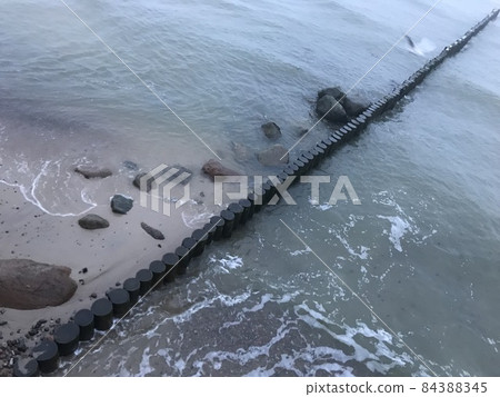 Breaking waves on a wooden breakwater on the Baltic Sea coast. 84388345