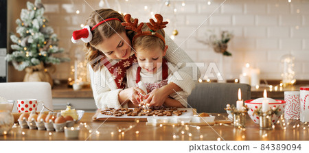 Happy family mother and son in aprons making Christmas cookies together at home Happy family mother and son in aprons making Christmas cookies together at home 84389094