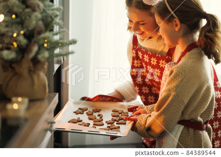 Happy family mother and daughter taking freshly baked Christmas cookies from oven 84389544