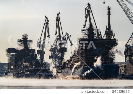 The construction of nuclear icebreakers, cranes of of the Baltic shipyard in a frosty winter day, steam over the Neva river, smooth surface of the river The construction of nuclear icebreakers, cranes of of the Baltic shipyard in a frosty winter day, steam over the Neva river, smooth surface of the river 84389625