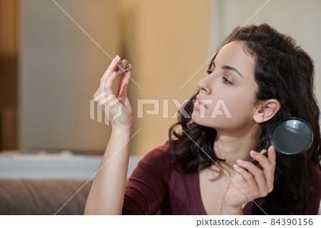 Woman concentrated on examining a beautiful amethyst Woman concentrated on examining a beautiful amethyst 84390156