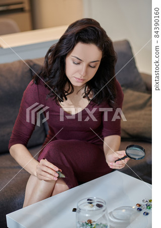 Serious beautiful lady examining a stone in her hand Serious beautiful lady examining a stone in her hand 84390160