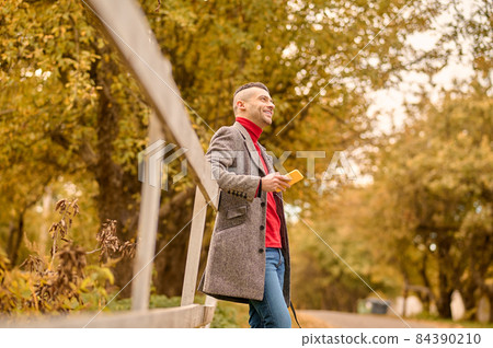 A man with a stylish haircut on the background of yellow leaves 84390210