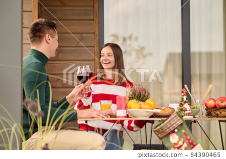 A couple sitting at the table with glasses of wine in hands A couple sitting at the table with glasses of wine in hands 84390465