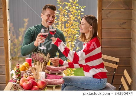 A couple sitting at the table with glasses of wine in hands A couple sitting at the table with glasses of wine in hands 84390474