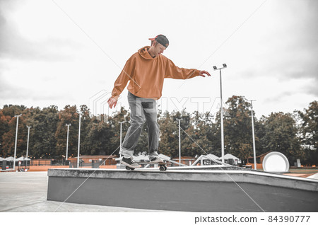 Guy on skateboard on bollard pushing off with foot 84390777