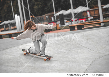 Girl on skateboard on bent legs rolling down Girl on skateboard on bent legs rolling down 84390818