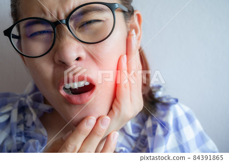 Close up of Asian woman having suffering from toothache. Toothaches can be caused by something happening to your teeth or gums. 84391865