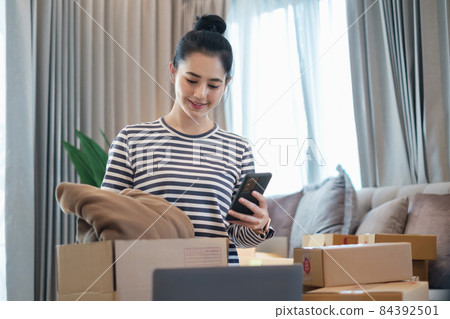 Asian small business owner checking order by smartphone at home office. Business retail market and online sell marketing delivery, SME e-commerce concept. 84392501