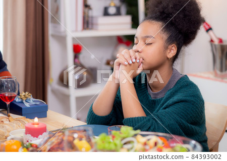 Happy African family holding hands and praying dinner on thanksgiving eve day together. Happy African family holding hands and praying dinner on thanksgiving eve day together. 84393002