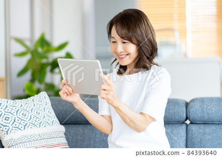 Senior woman operating a tablet in the living room 84393640