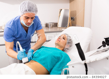 Woman receiving body ultrasound lifting procedure Woman receiving body ultrasound lifting procedure 84394027