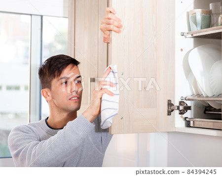 Male is caring about clean of kitchen at her house 84394245