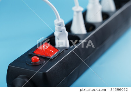 Surge protector with connected white wires of electrical appliances on a blue background. Surge protector with connected white wires of electrical appliances on a blue background. 84396032