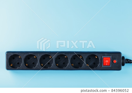 A black surge protector with portable sockets and a red button on a blue background. 84396052