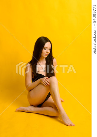 A sexy model posing in a black bodysuit againts a yellow background. A sexy model posing in a black bodysuit againts a yellow background. 84399773