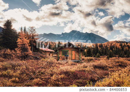 Wooden huts with rocky mountains in autumn forest at Assiniboine provincial park 84400853