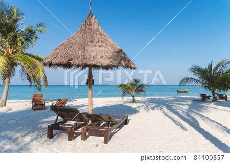 Wooden lounge under thatched umbrella on the beach in tropical sea at Lipe island Wooden lounge under thatched umbrella on the beach in tropical sea at Lipe island 84400857