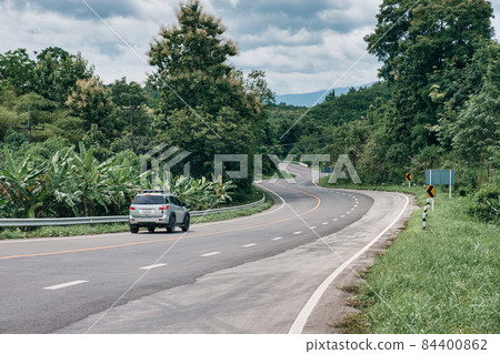 Car driving on winding road on top of mountain in tropical rainforest at Nan province 84400862