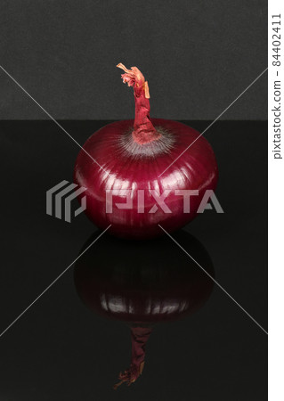Red onion bulb isolated on acrylic black background. 84402411