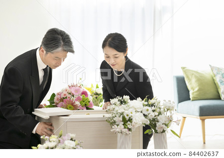 Middle-aged men and women looking inside the casket, family funeral, home funeral image Middle-aged men and women looking inside the casket, family funeral, home funeral image 84402637