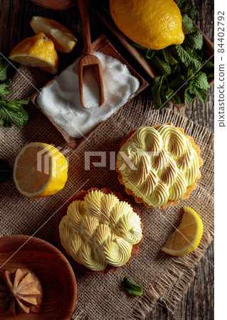 Tartlets with lemon cream and mint on a old wooden table. 84402792