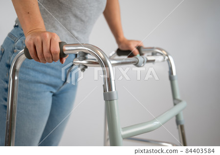 A woman is walking with a walker on a white background A woman is walking with a walker on a white background 84403584