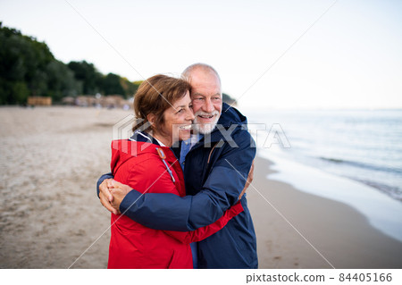 Happy senior couple in love embracing when walking on sandy beach in autumn. 84405166