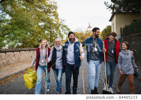 Diverse group of happy volunteers walking with tools to do street clean up, community service concept 84405215