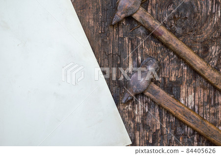 Old rusty hand tools. Two hammers and a sheet of paper on a crac Old rusty hand tools. Two hammers and a sheet of paper on a crac 84405626